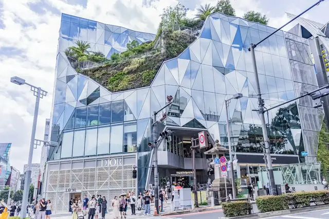 Angular mirrored entrance and rooftop greenery at the Harajuku Omotesando intersection
