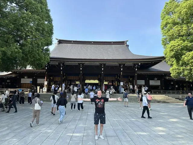 Visitor with arms outstretched in the courtyard of Meiji Jingu