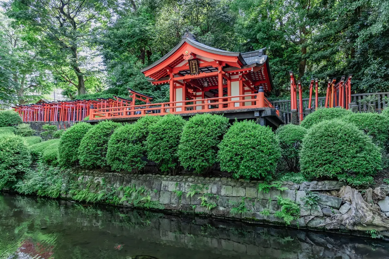 Red shrine and torii gates among the greenery of Nezu Shrine in Tokyo