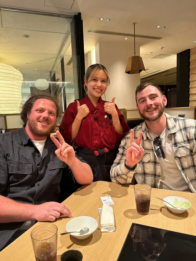 Three people smiling together at a Japanese restaurant in Tokyo